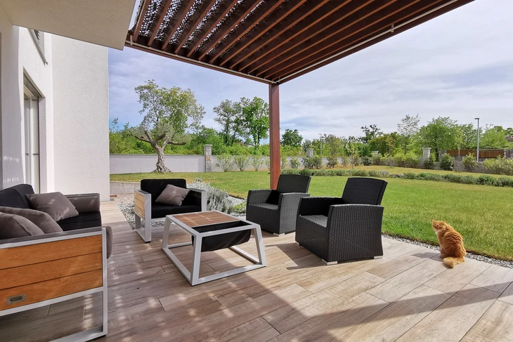 Terrasse moderne couverte avec pergola à lames bois, mobilier de jardin contemporain noir et structure métallique blanche