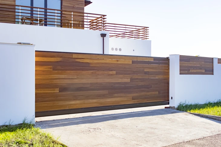 Entrée résidentielle moderne avec portail coulissant automatique en bois exotique aux lames horizontales de teintes variées