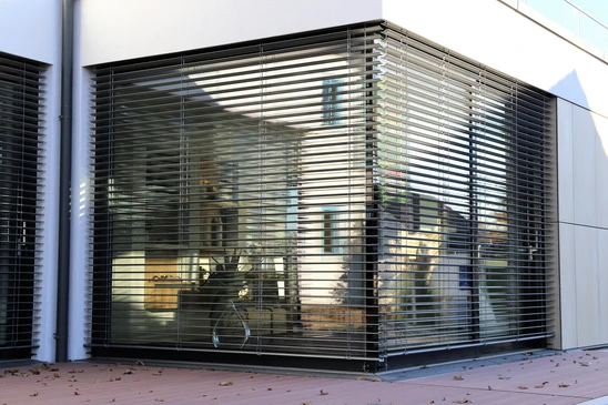Façade commerciale moderne avec rideaux métalliques de sécurité fermés protégeant une vitrine d'entreprise