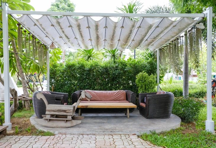 Espace de détente extérieur avec salon de jardin sous pergola blanche à toile rétractable