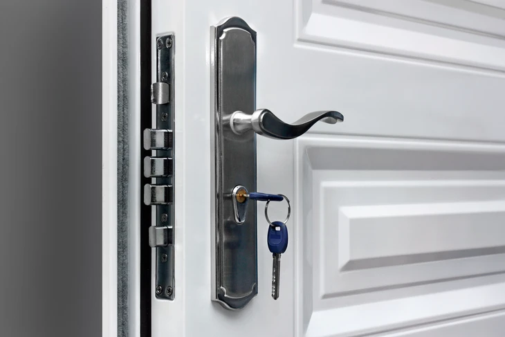Porte d'entrée blanche entrouverte avec serrure de sécurité moderne