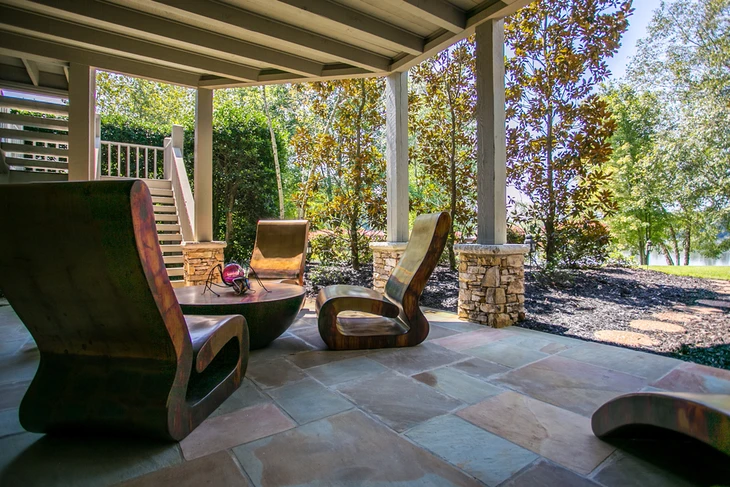 Terrasse couverte moderne avec fauteuils design en bois courbé disposés autour d'une table basse circulaire
