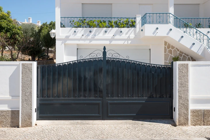 Entrée résidentielle avec grand portail métallique noir orné de ferronnerie décorative