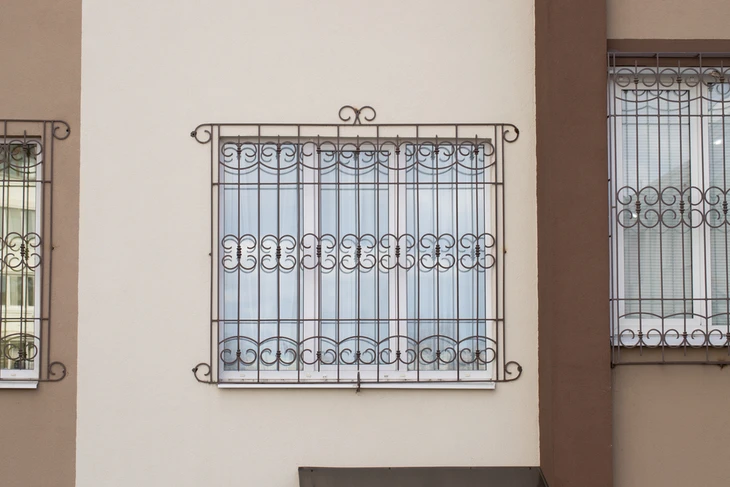 Façade extérieure d'habitation avec fenêtres protégées par des grilles décoratives en fer forgé