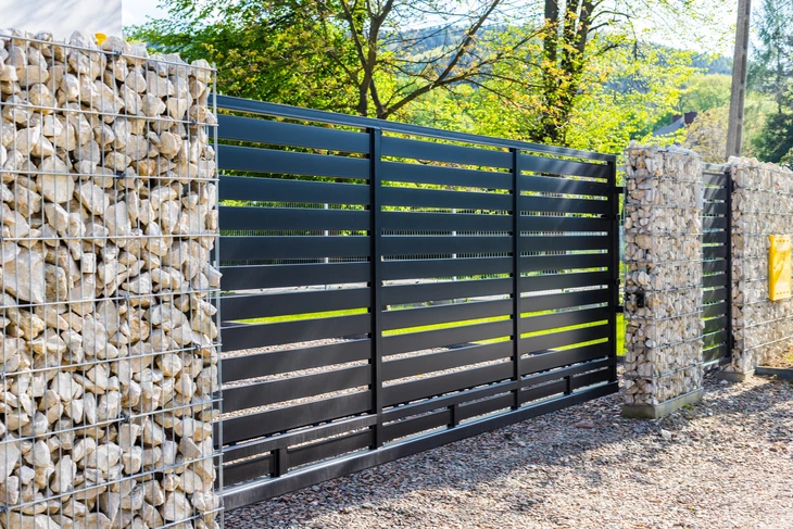 Scène extérieure résidentielle avec portail coulissant moderne en aluminium anthracite à lames horizontales ajourées