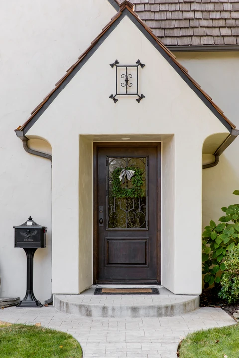 Entrée principale d'une maison résidentielle avec porte en bois foncé ornée d'une couronne décorative