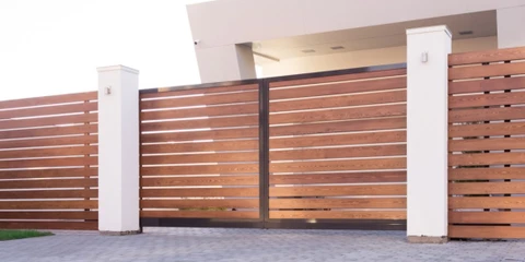 Entrée résidentielle moderne avec portail double battant en bois foncé, piliers en béton blanc et murs en briques grises