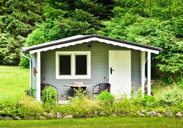 Abri de jardin en bois avec terrasse couverte dans un environnement paysager verdoyant