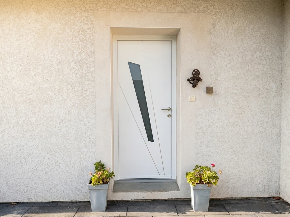 Entrée extérieure d'une maison, porte d'entrée moderne blanche avec vitrage intégré en verre fumé trapézoïdal et incisions décoratives en V